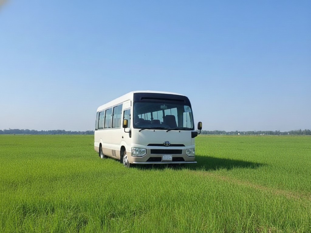 White Toyota Coaster tourist bus parked in a field in Bangladesh